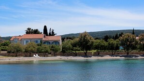 A coastal property with a large house, a beach, and a clear view of the sea.