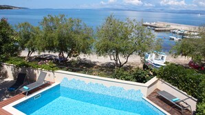 A swimming pool with a view of the sea and boats.
