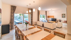 A spacious living area with a dining table, sofas, and a kitchen area.