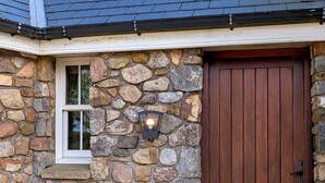 Ein Steinhaus mit einer Holztür und einem Fenster mit Wandleuchte.