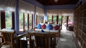 Um quarto com sofá, cadeiras, uma mesa e estante.