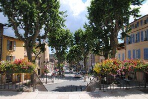 A tree-lined street with buildings on either side, a pedestrian walkway, and parked cars. - Superb villa with quiet pool while being close to the city center (Lorgues)