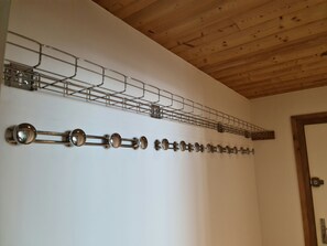 Ein Zimmer mit Holzbalkendecke und weißer Wand. An einem Metallgestell sind mehrere runde Objekte befestigt.