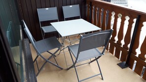 Un piccolo patio esterno con un tavolo e quattro sedie.
