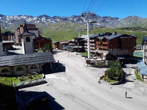 Un paese di montagna con una seggiovia, edifici dalle facciate in legno e una vista chiara di montagne innevate sullo sfondo.