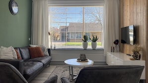 Un salon moderne avec un canapé, des fauteuils, une table basse et un téléviseur.