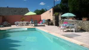 A swimming pool with lounge chairs and umbrellas, surrounded by stone walls and a building with a bicycle symbol. - 🌸 La Maison Rose – Your Dream French Countryside Escape 🌸 (Marsac)