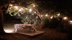 An outdoor dining area with a table and chairs under a tree, illuminated by string lights. - 🌸 La Maison Rose – Your Dream French Countryside Escape 🌸 (Marsac)