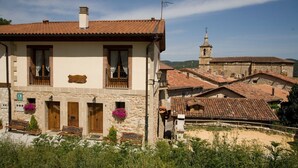 Un bâtiment traditionnel en pierre, doté d’un toit en tuiles, d’un clocher et d’un petit balcon orné d’une balustrade en bois.