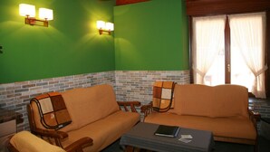 Une pièce avec deux canapés, une table sur laquelle se trouve un livre et deux lampes fixées au mur.