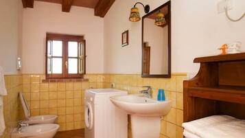 Ein kleines Badezimmer mit Waschmaschine, zwei Waschbecken, Toilette und Holzboden.