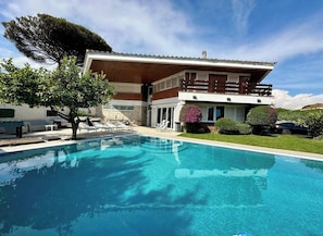 A modern two-story house with a swimming pool, outdoor furniture, and a well-maintained garden.