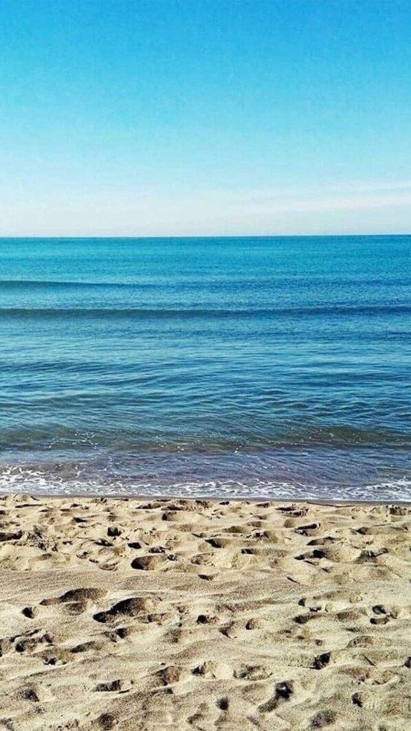 Una playa con huellas en la arena y un mar tranquilo.