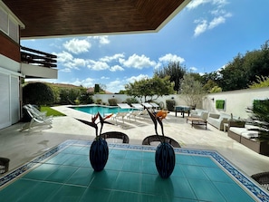 A poolside area with a tiled patio, two vases, outdoor furniture, and a view of the swimming pool. -  Luxury villa a few meters from the sea, whirlpool and private swimming pool (Fregene)