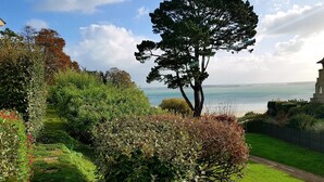 A garden with a large tree, a pathway, and a view of the sea. - Residential flat- ST-CAST-LE-GUILDO (Saint-Cast-le-Guildo)