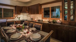 Una cocina moderna con armarios de madera oscura, una isla grande con asientos y un comedor listo para una comida.