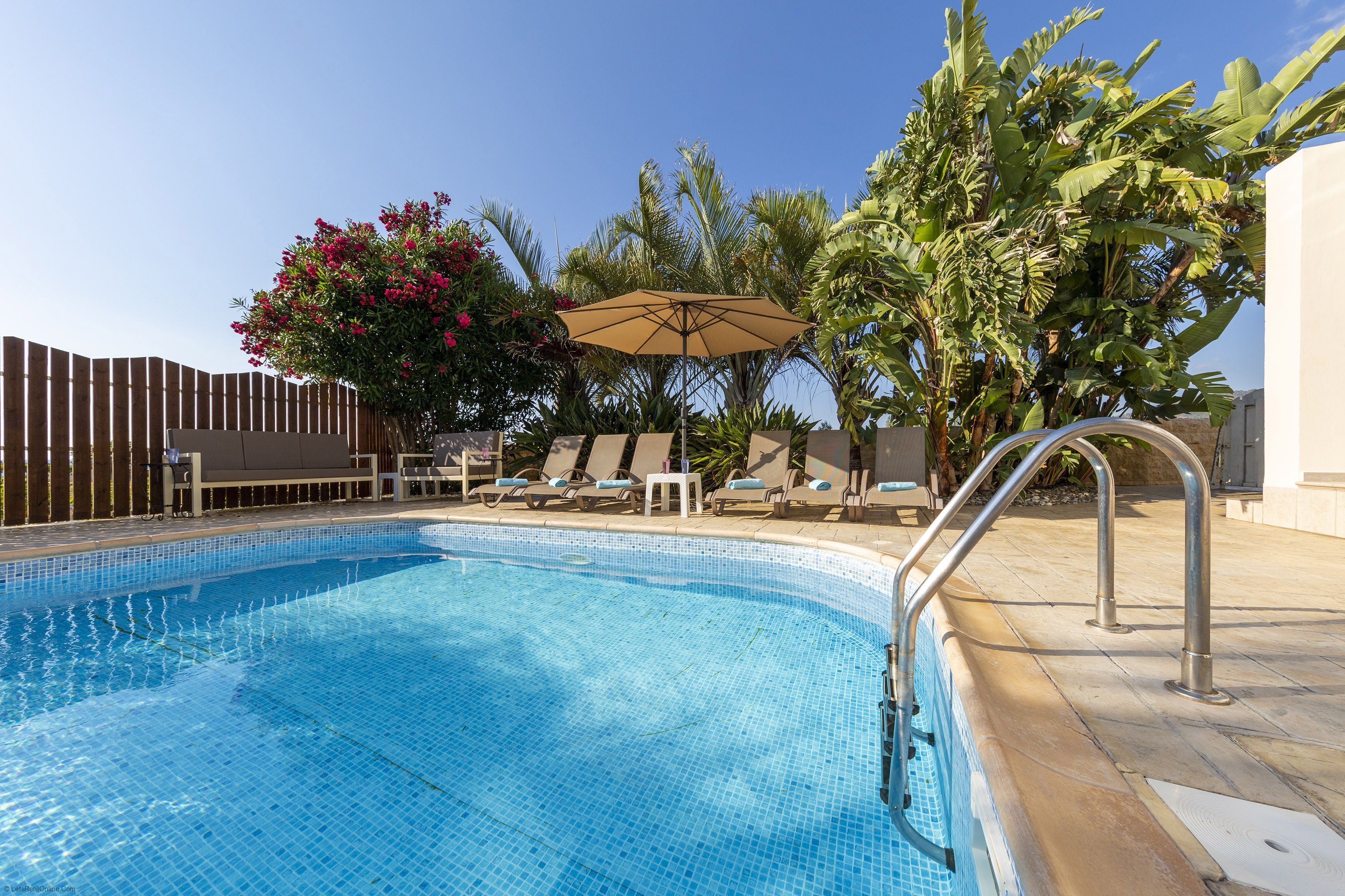 A swimming pool with lounge chairs and an umbrella.