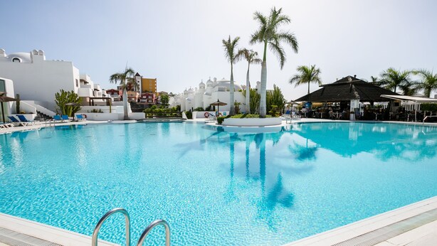 A large, clear swimming pool with a poolside area, palm trees, and a bar area. - 3 bedroom apartment with sunny terrace perfect for families (Costa Adeje)