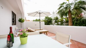 A patio with a table, chairs, a bottle of champagne, a potted plant, and an umbrella. - 3 bedroom apartment with sunny terrace perfect for families (Costa Adeje)