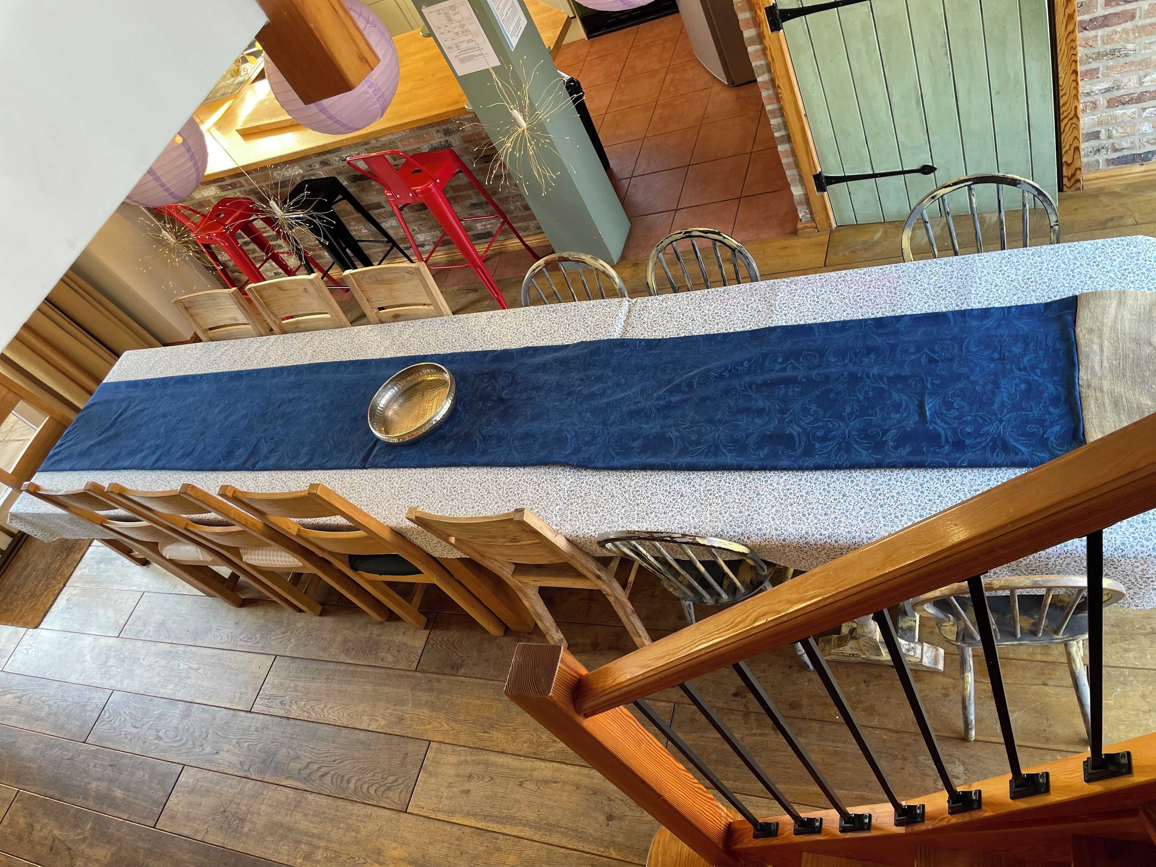 Un espace repas comprenant une longue table, des chaises et un chemin de table bleu décoratif.