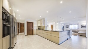 A modern kitchen with built-in appliances, a central island, and a dining area with a sofa. - Your private getaway in Vale do Lobo (Vale do Lobo)