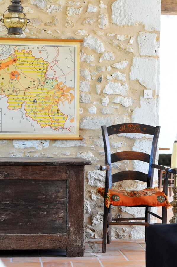 Un mapa en la pared, una silla de madera con cojín y una pared de piedra.