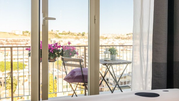 A balcony with a chair, a small table, and potted plants.