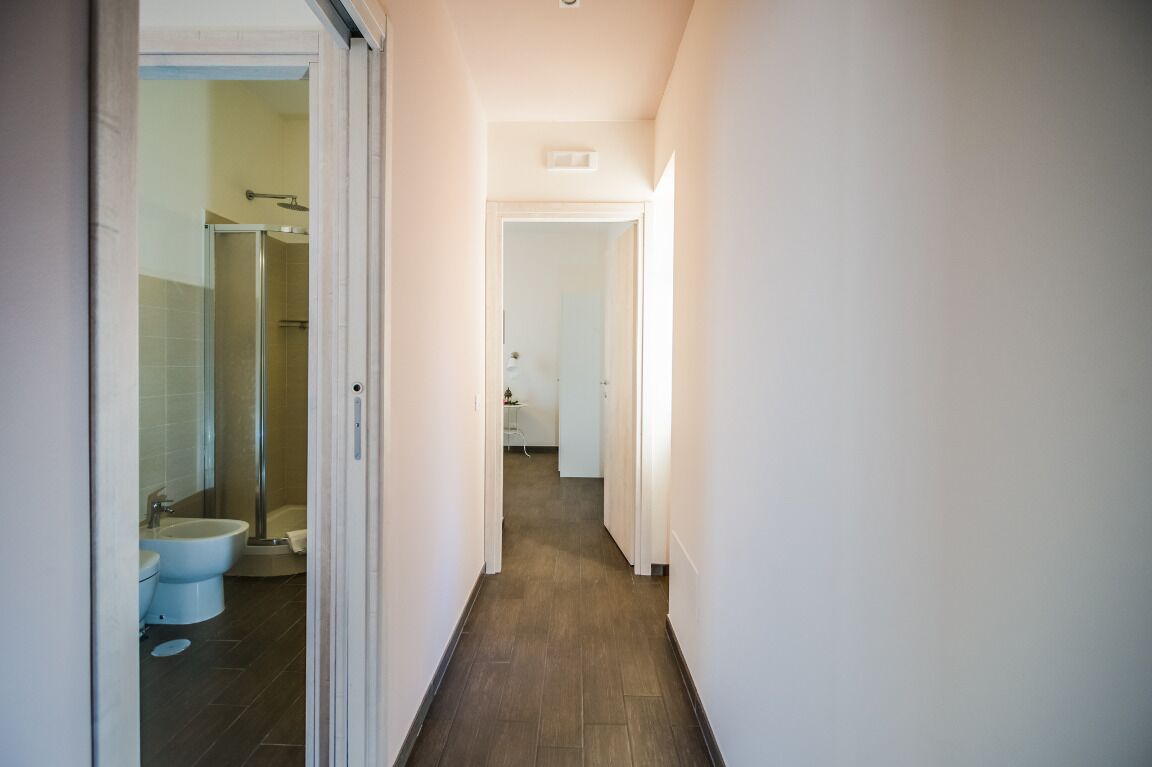 Un estrecho pasillo que lleva a un baño con inodoro, bidé y ducha.