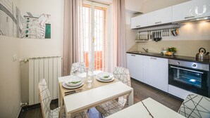 A modern kitchen with white cabinets, a built-in oven, and a dining area with a table and chairs.