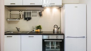 A modern kitchen with white cabinets, a stainless steel range, a built-in oven, and a white refrigerator.