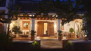 Ein Gebäude mit überdachter Terrasse, Holztüren und Blumentöpfen.