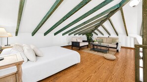 A loft bedroom with a sloped ceiling, wooden beams, a bed, a sofa, a coffee table, and a lamp. - CERCADO DEL MEDIO COUNTRY VILLA AND POOL (Adeje)