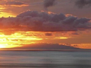 A sunset over a calm sea with clouds in the sky.