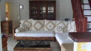 Una sala de estar con un sofá, una mesa de centro de madera, un armario y una escalera.