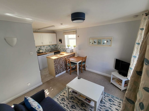 Un espacio habitable compacto con kitchenette, comedor y televisor.