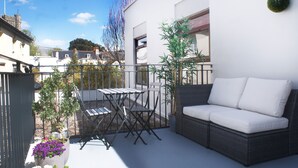 Een balkon met een rieten bank, een tafel en stoelen.