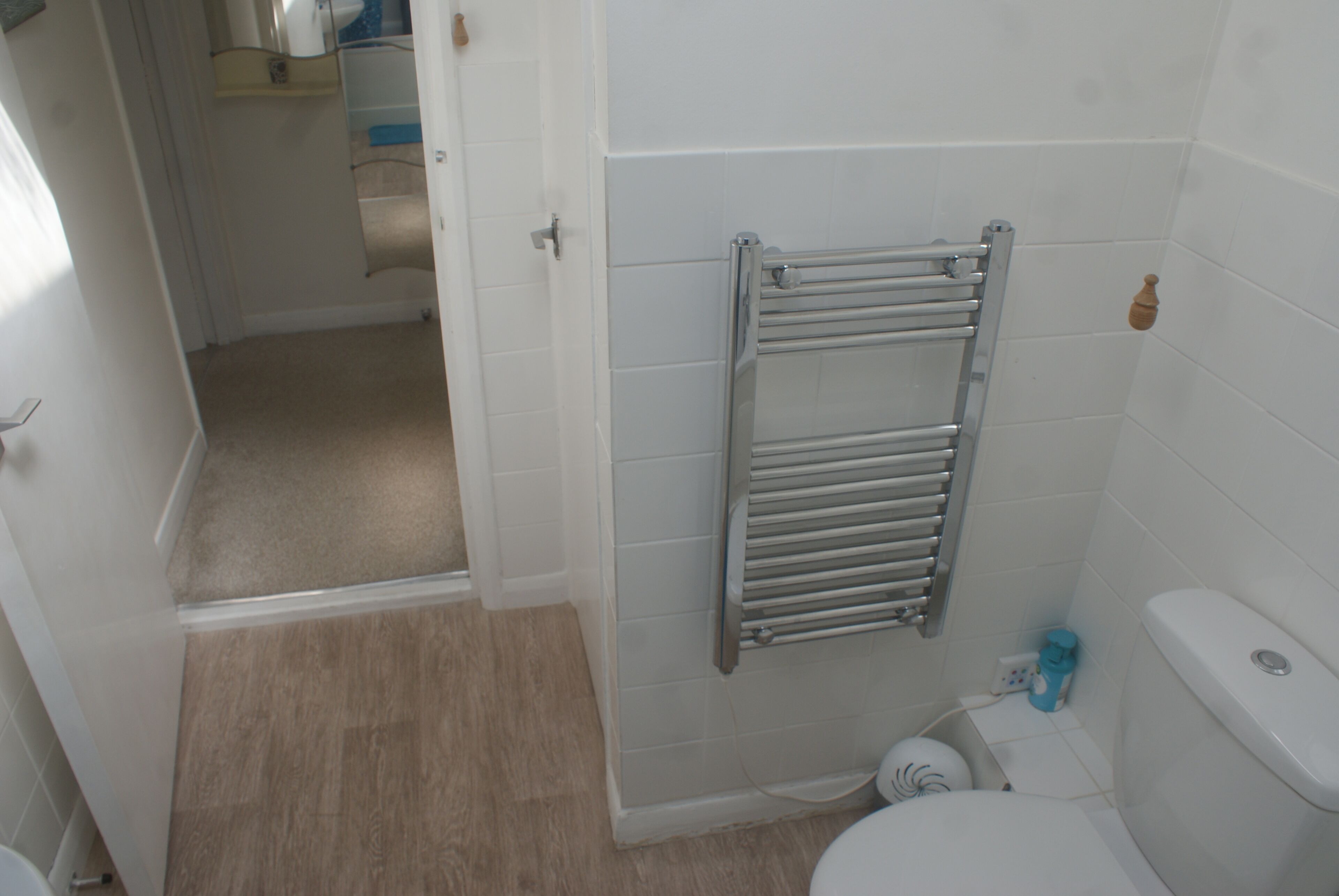 Une salle de bain avec des toilettes blanches, un porte-serviettes et un espace douche.