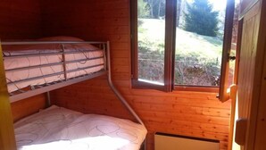 Een kleine eenpersoonskamer met een stapelbed, een raam met uitzicht op de omgeving, en een radiator op de vloer.