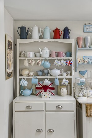 A white cabinet with multiple shelves holding various kitchenware items.