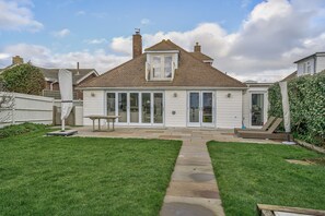 A two-story house with a covered patio, a small garden, and a visible garage.