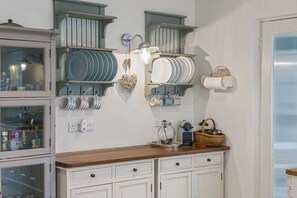 A kitchen with white cabinets, a wooden countertop, and hanging utensils.