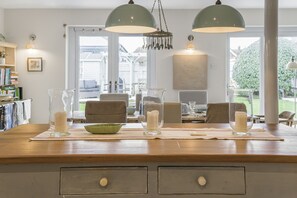 A kitchen with a wooden countertop, two pendant lights, and a view of the backyard through the window.