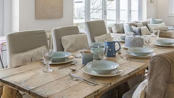 Une table à manger dressée avec des assiettes, des verres et des couverts, entourée de chaises.