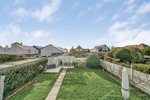 A residential backyard with a patio, a pergola, and a well-maintained lawn. - Lumiere - West Wittering (West Wittering, West Sussex)