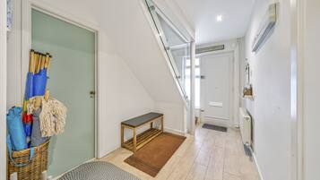 Un couloir avec un banc en bois, un panier en osier et une porte dotée d’un porte-serviettes.
