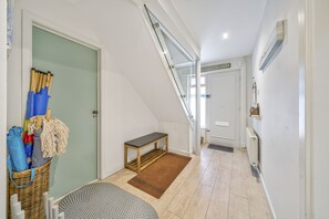 A hallway with a wooden bench, a wicker basket, and a door with a towel rack.