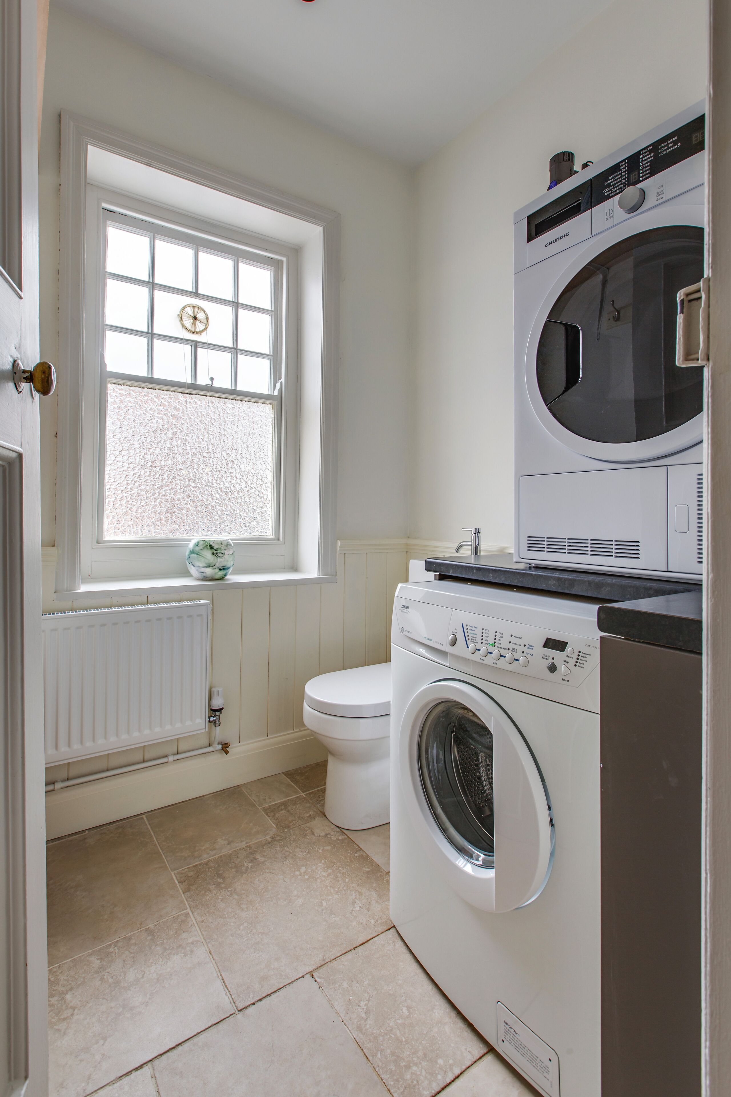 A compact laundry room with a washing machine, dryer, and a window with a view.