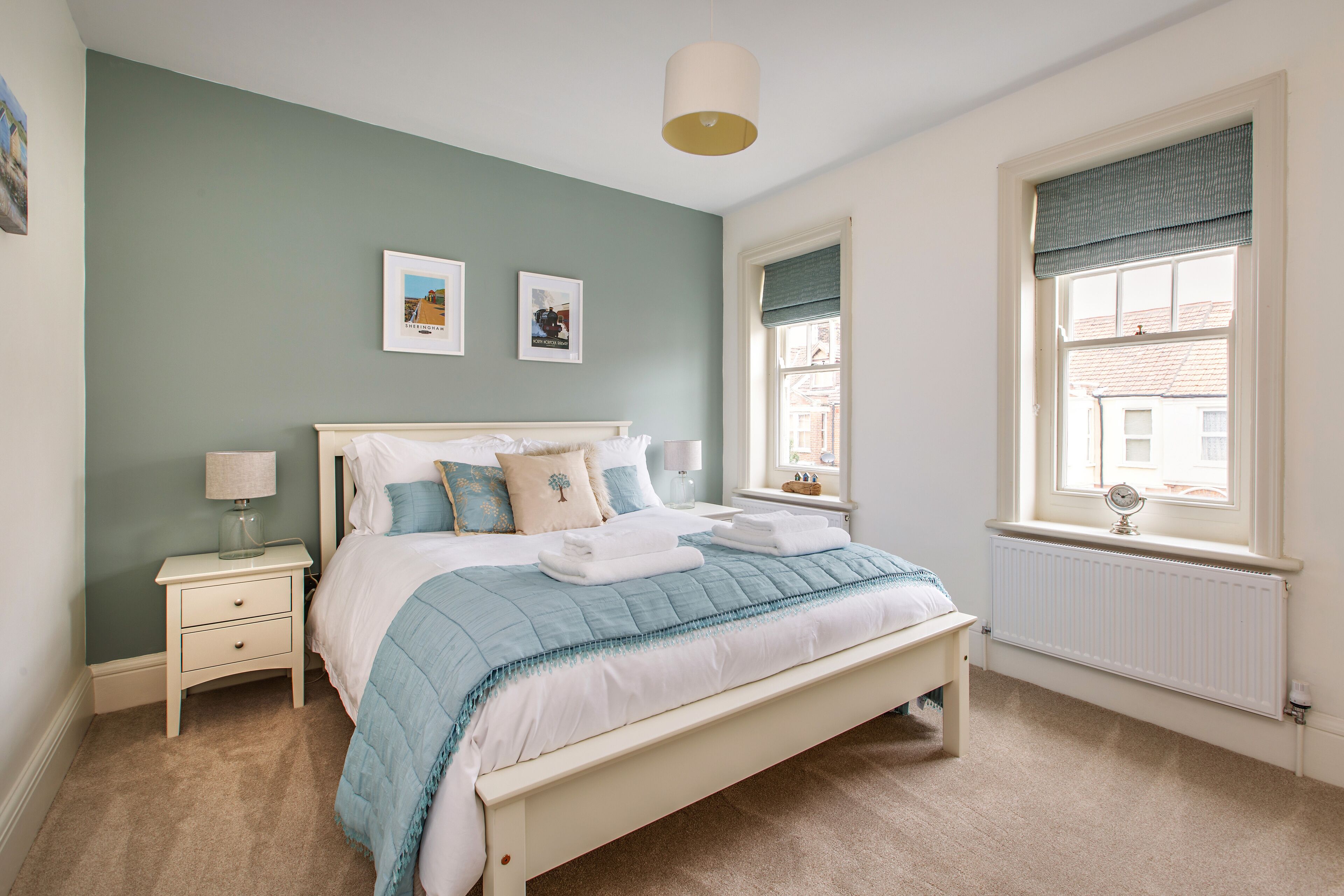 A bedroom with a bed, bedside tables, a window with a view, and wall art.