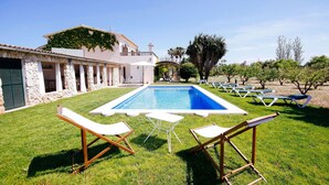 Una piscina con sillas de descanso y un edificio de piedra con columnas.