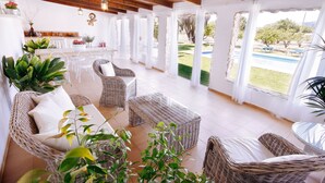 Un amplio patio con muebles de mimbre, una piscina y vistas al jardín.